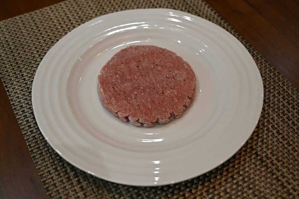 Top down image of one frozen lean sirloin beef patty served on a plate. 