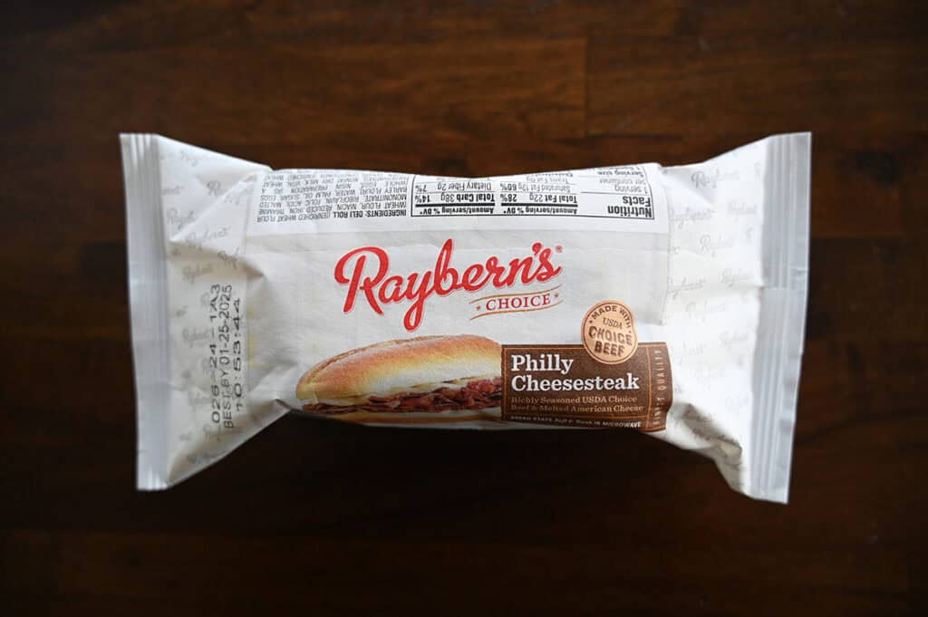 Image of one individually wrapped Philly cheesesteak sitting on a table unopened.