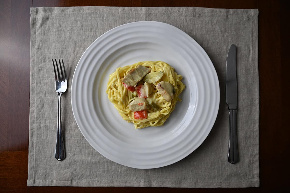 Top down image of one plate of tagliolini sitting on a placemat beside a fork and knife.