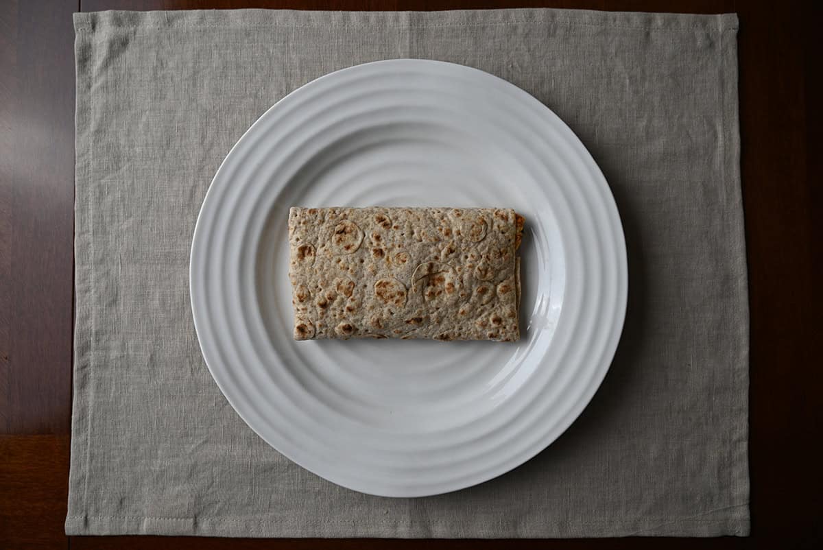 Top down image of one breakfast wrap heated and served on a white plate.