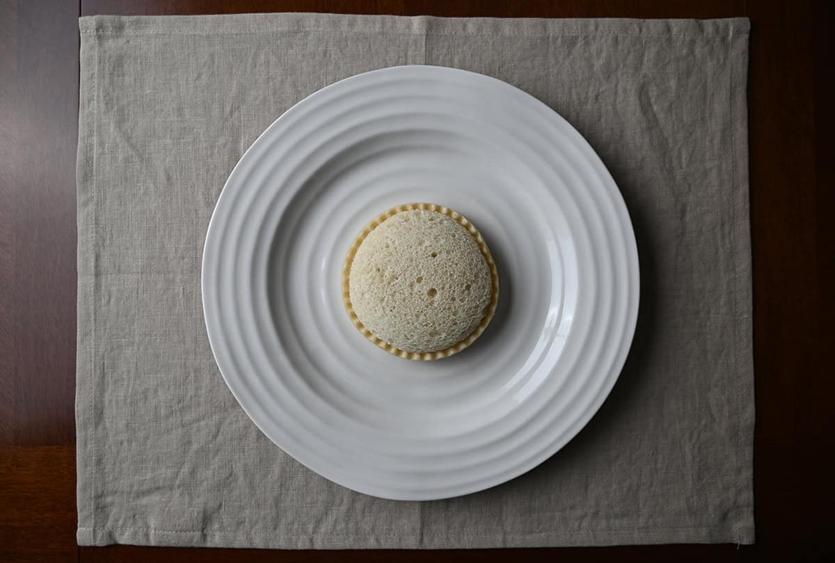 Top down image of one Smucker's Uncrustable unwrapped and sitting on a white plate. 