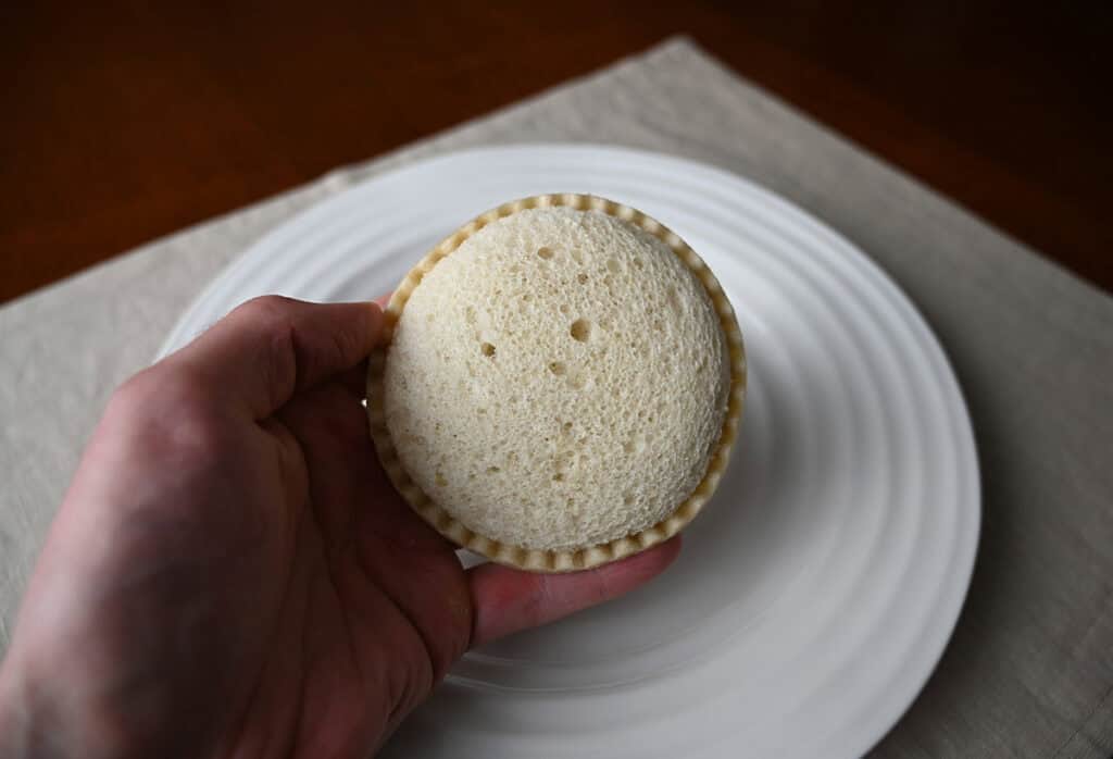 Image of a hand holding on whole Uncrustable close to the camera. 