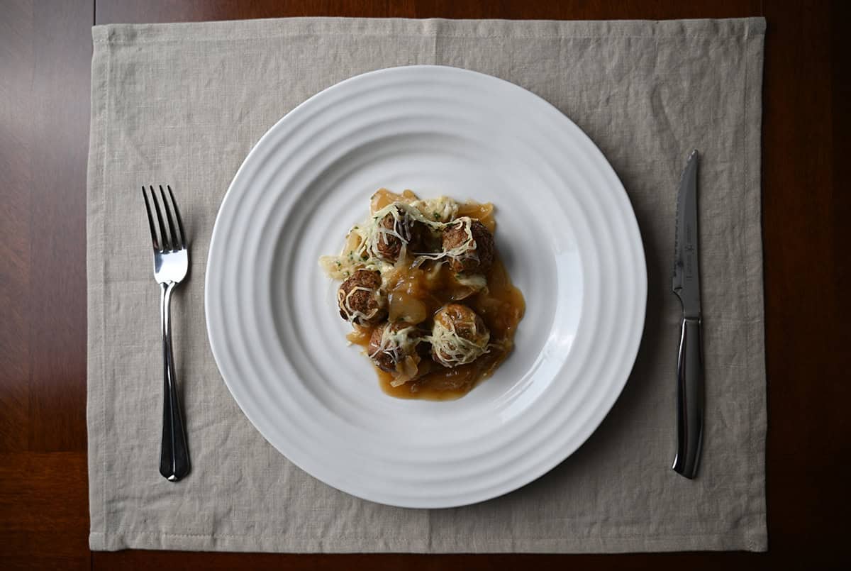 Top down image of a plate of six meatballs served on it with onions and cheese.