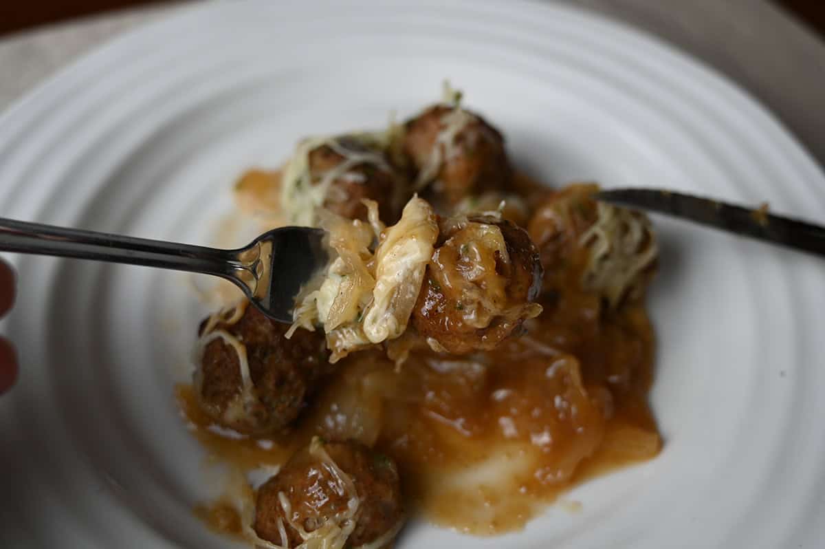 Closeup image of a fork with some of the cheese and onions from the meatball bake on it. 