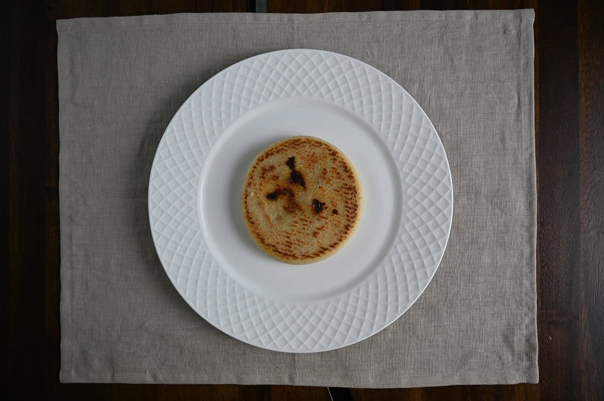 Top down image of one pupusa served on a white plate.