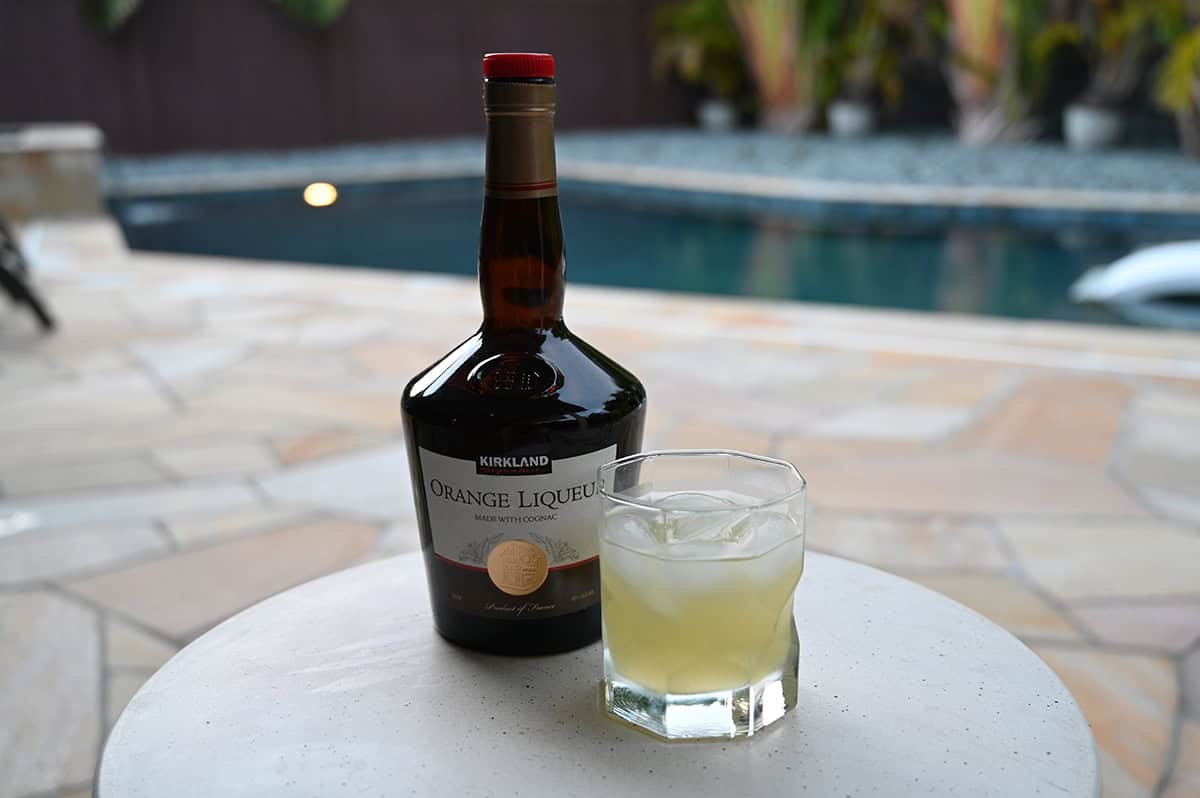 Image of a bottle of Kirkland Signature Orange Liqueur sitting beside a glass with a margarita in it.