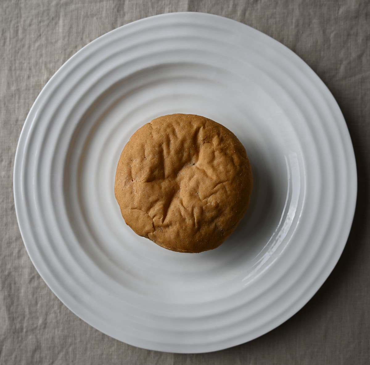 Image of one hamburger bun sitting on a table.