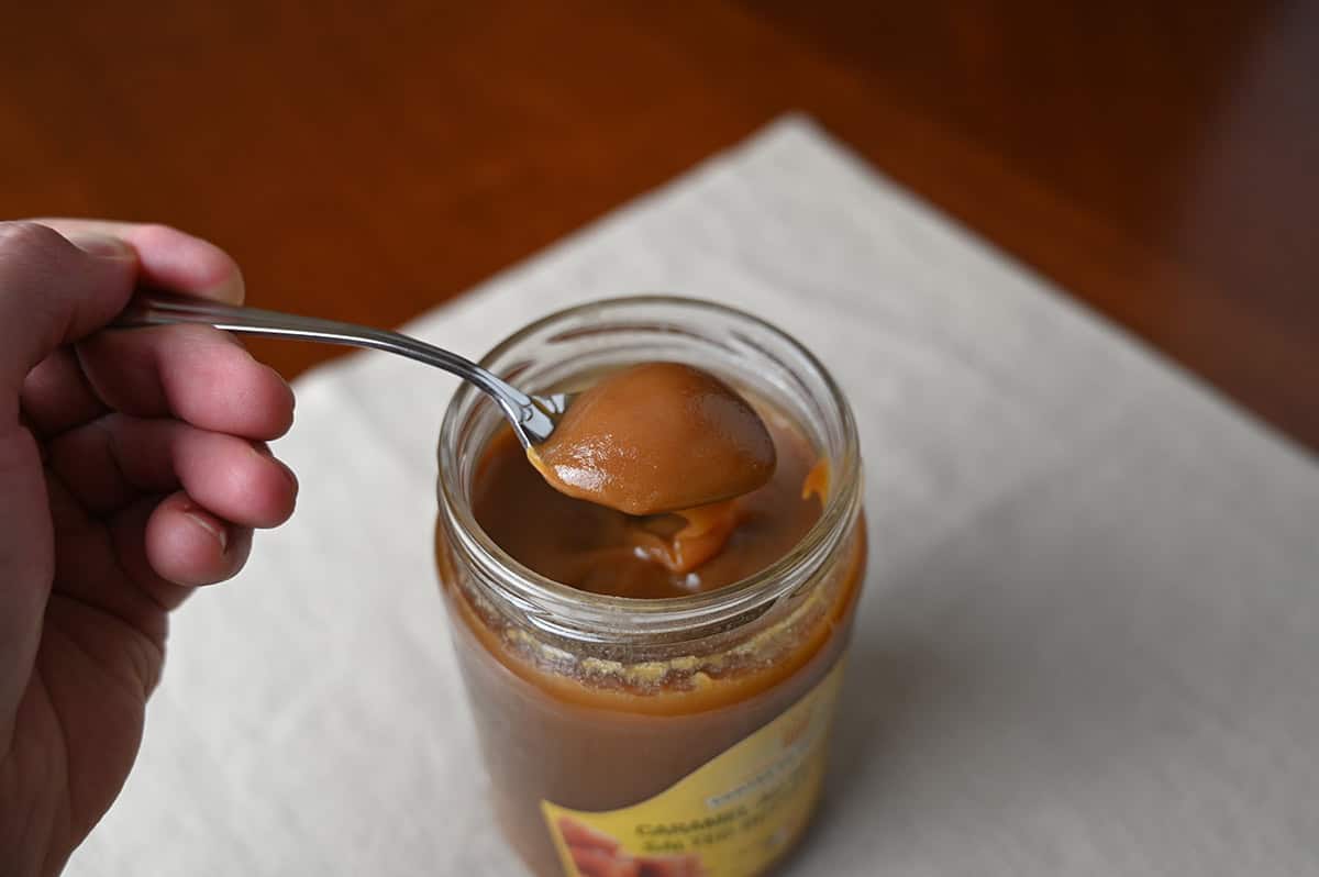 Image of a spoon scooping salted caramel out of a jar. 