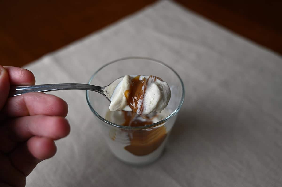 Image of a spoon scooping ice cream with caramel sauce on it out of a bowl.