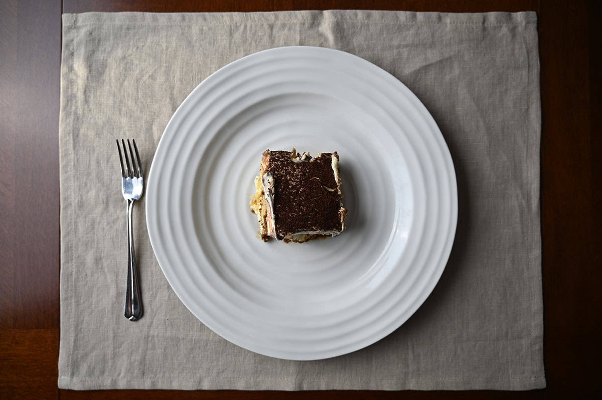 Image of a slice of Tiramisu Scoop Cake served on a white plate beside a fork.