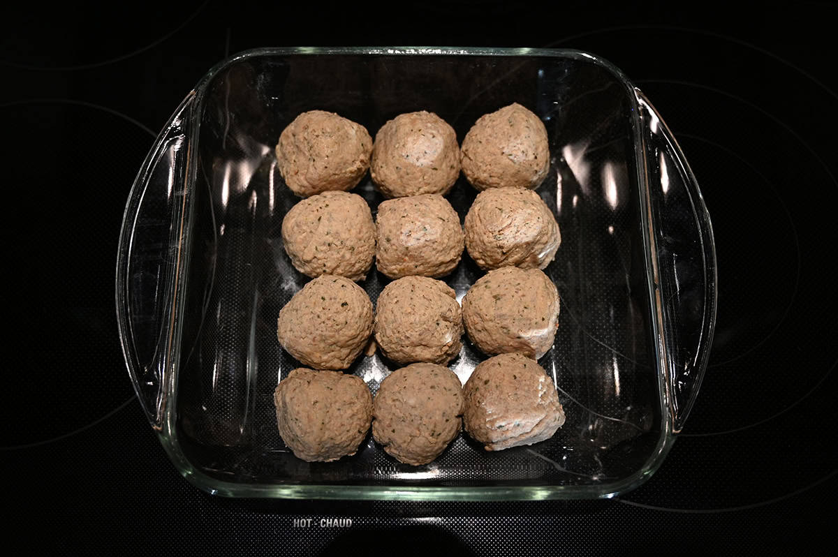 Image of 12 meatballs in a baking dish prior to cooking them in the oven.