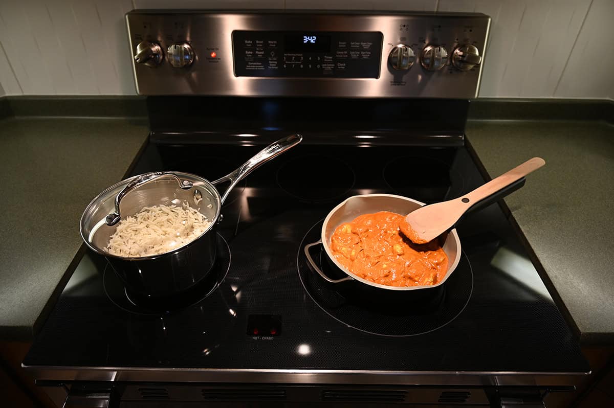 Image of a pot of rice beside a pan with curry in it cooking on the stovetop.