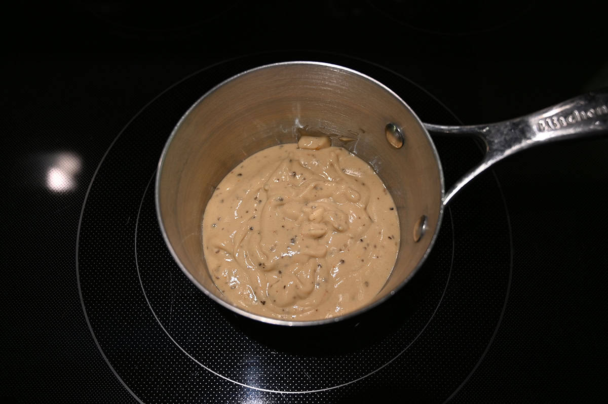 Image of a saucepan on a stovetop with mushroom sauce heating in it.