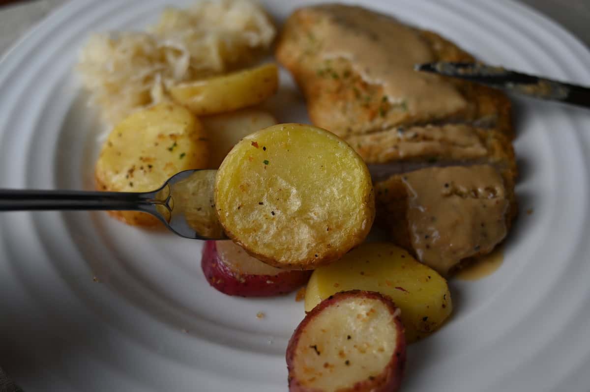 Image of a fork with a slice of potato on it hovering over a plate of pork schnitzel. 