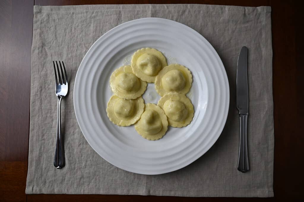 Top down image of a plate of ravioli with a butter sauce on it served on a white plate. 