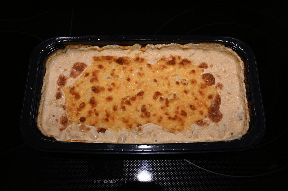 Top down image of a container of bacon macaroni and cheese with the plastic seal taken off prior to baking it. 