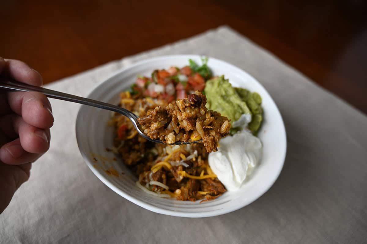 Image of a fork hovering over a bowl of burrito rice mixture, on the fork is rice and beef.