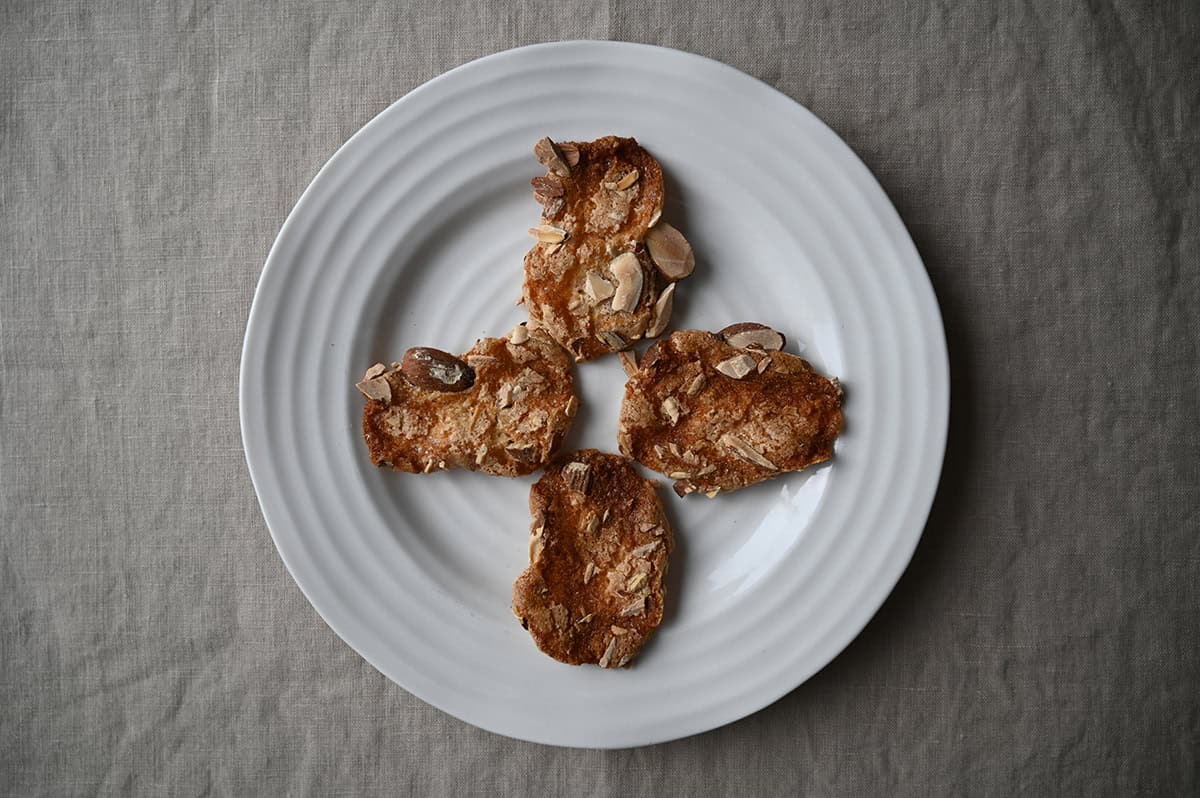 Image of a white plate with four almond crisps served on it. 