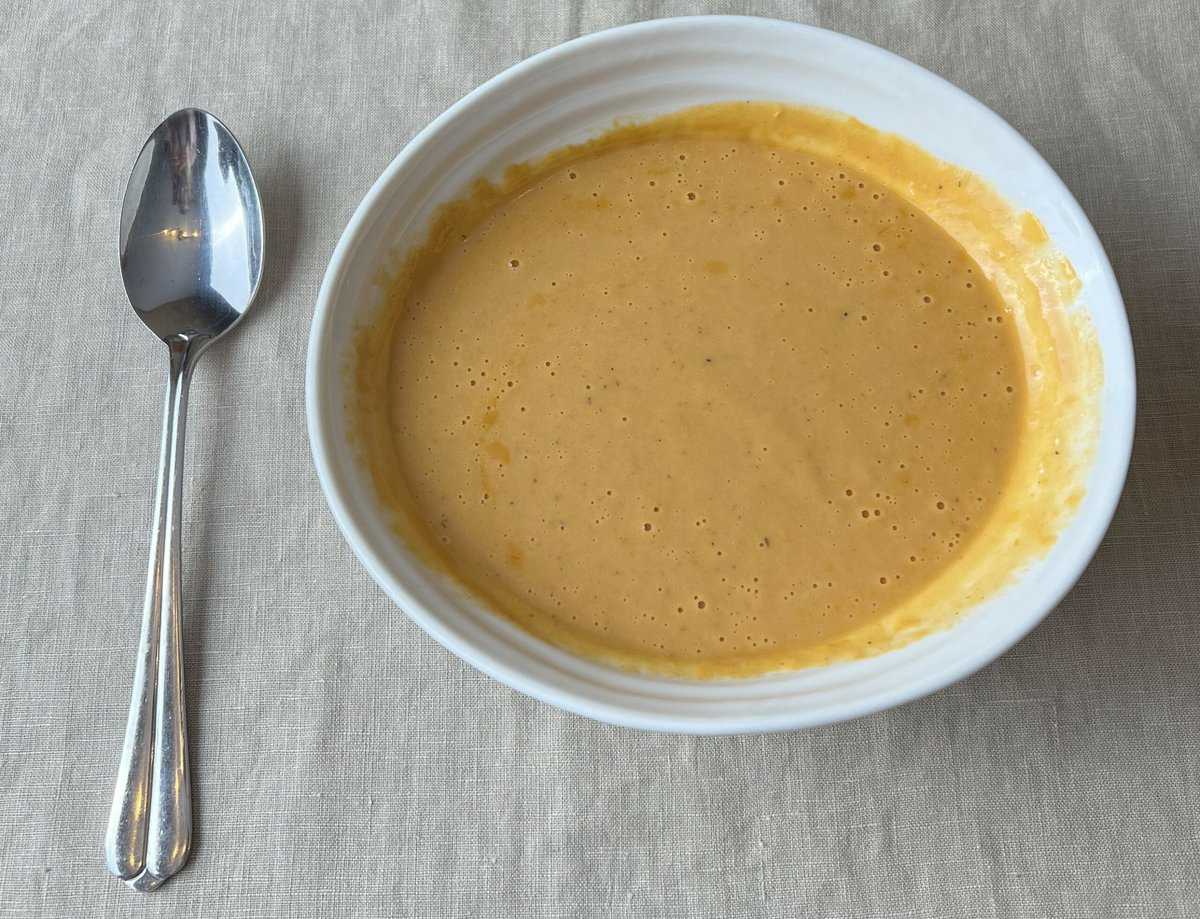 Image of a bowl of lobster bisque with a spoon resting beside the bowl.