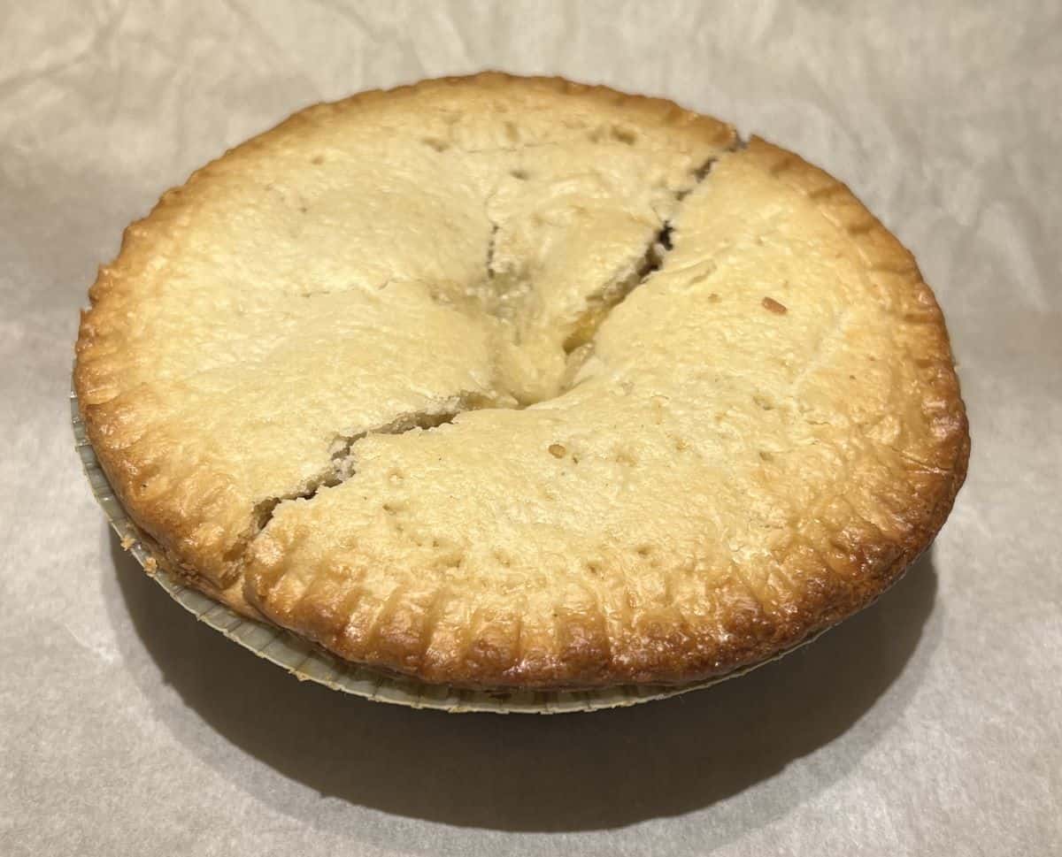 Image of a meat pie coming out of the oven with a crack down the center. 