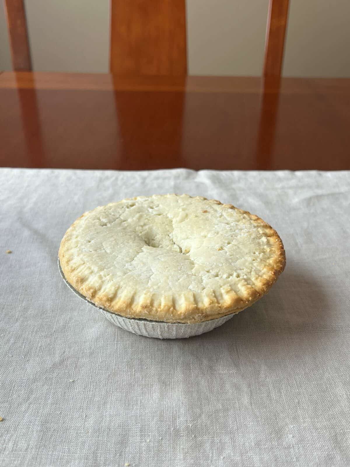 Image of one uncooked meat pie sitting on a table.