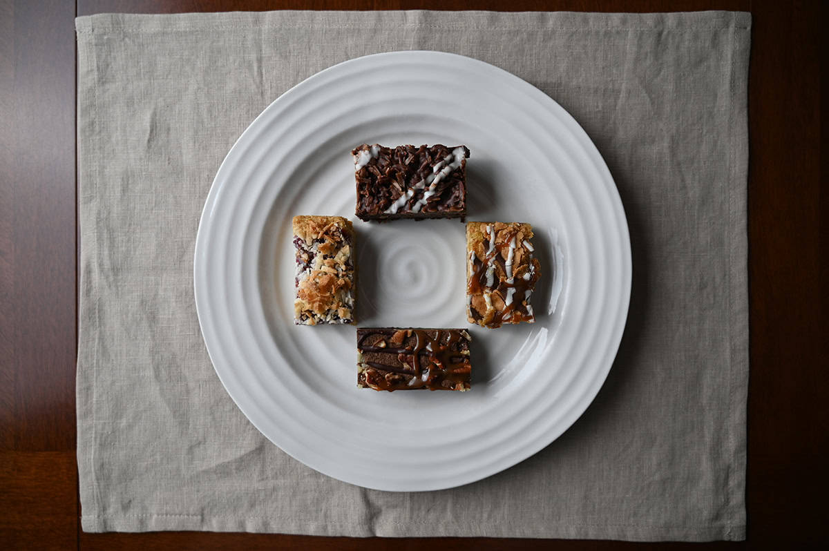 Top down image of four dessert bars served on a white plate. 