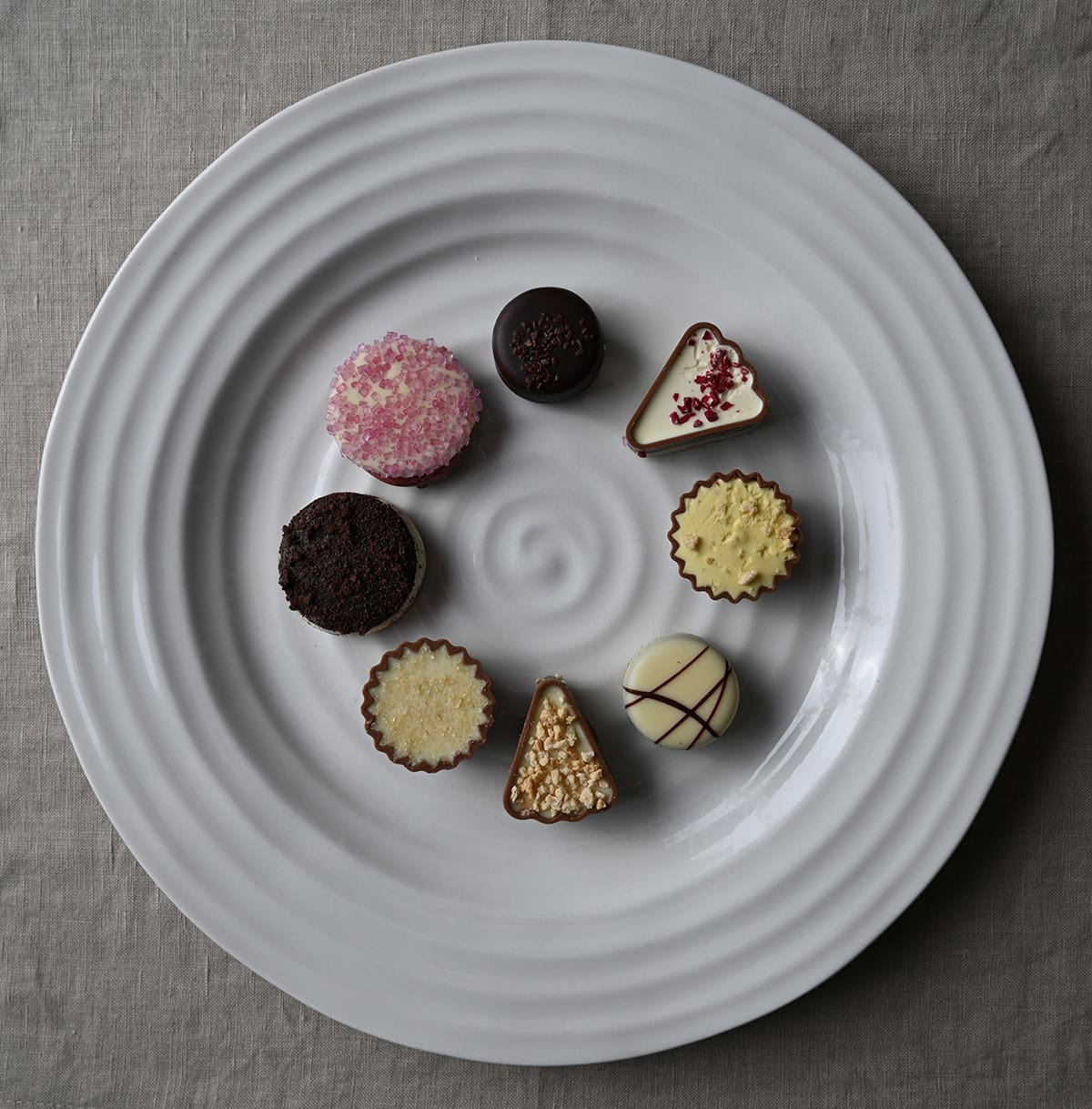 Image of a white plate with chocolates served on it in various flavors and colors. 