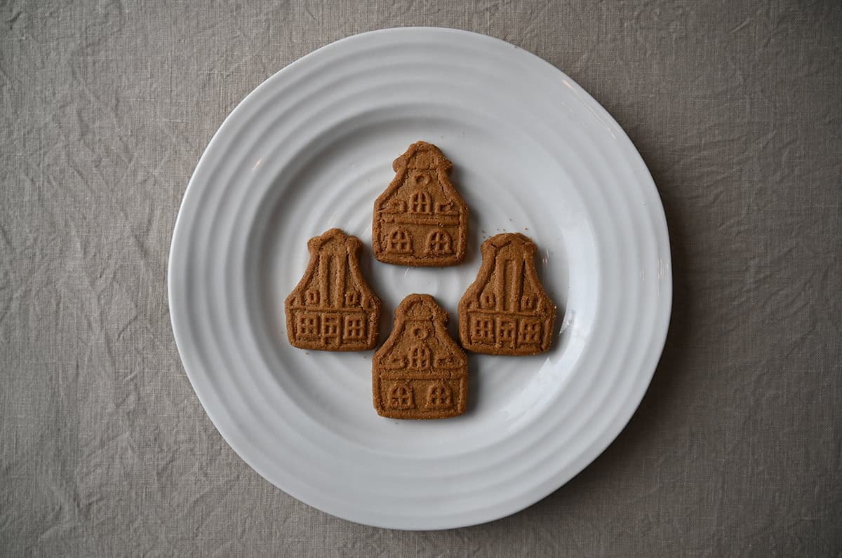 Top down image of four cookies served on a white plate, the cookies are shaped like a house.