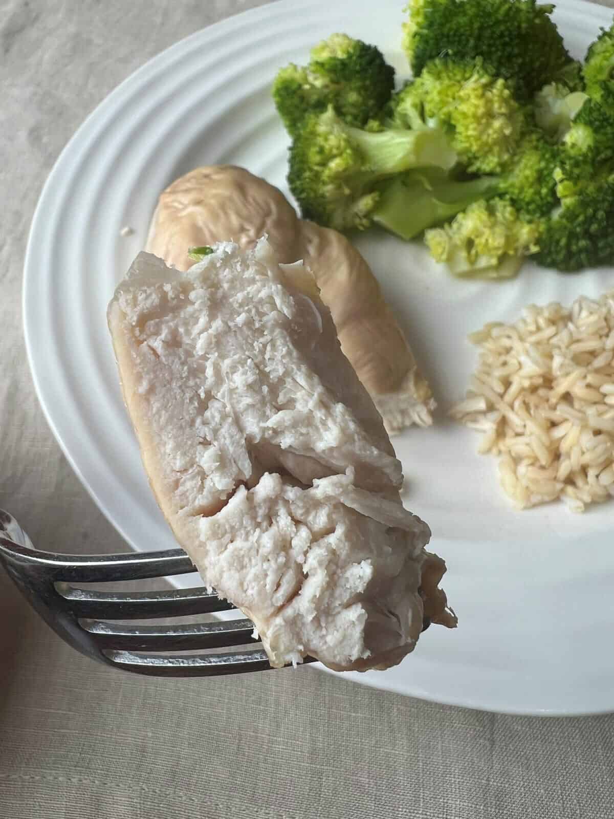 Closeup image of a piece of chicken breast on a fork showing what the inside of the chicken breast looks like.