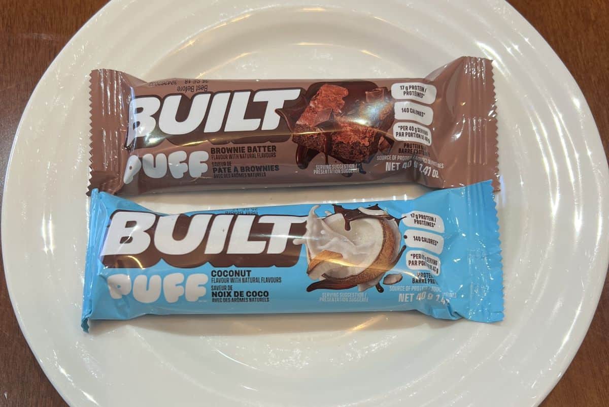 Top down image of two Built Puff Protein Bars still in their packaging and served on a white plate. 