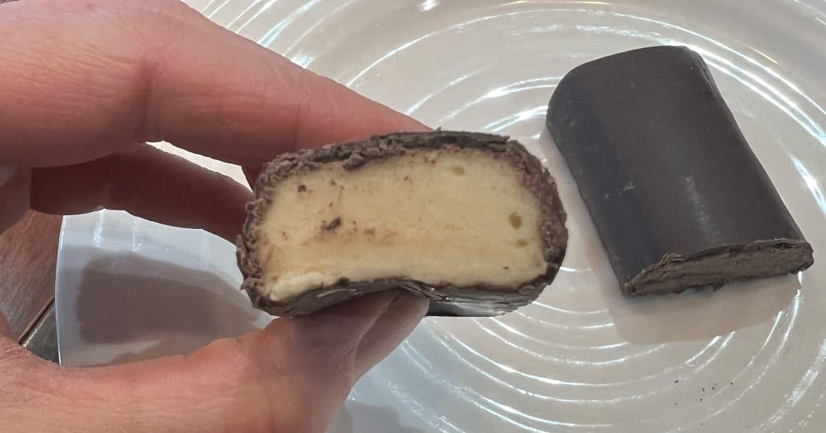 Image of a hand holding one Built Puff Coconut Protein Bar with a few bites taken out so you can see the center.