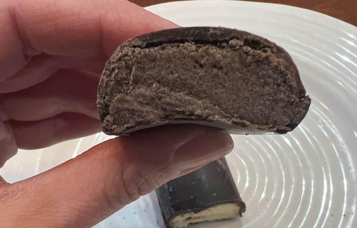 Image of a hand holding one Built Puff Brownie Batter Protein Bar with a few bites taken out so you can see the center.