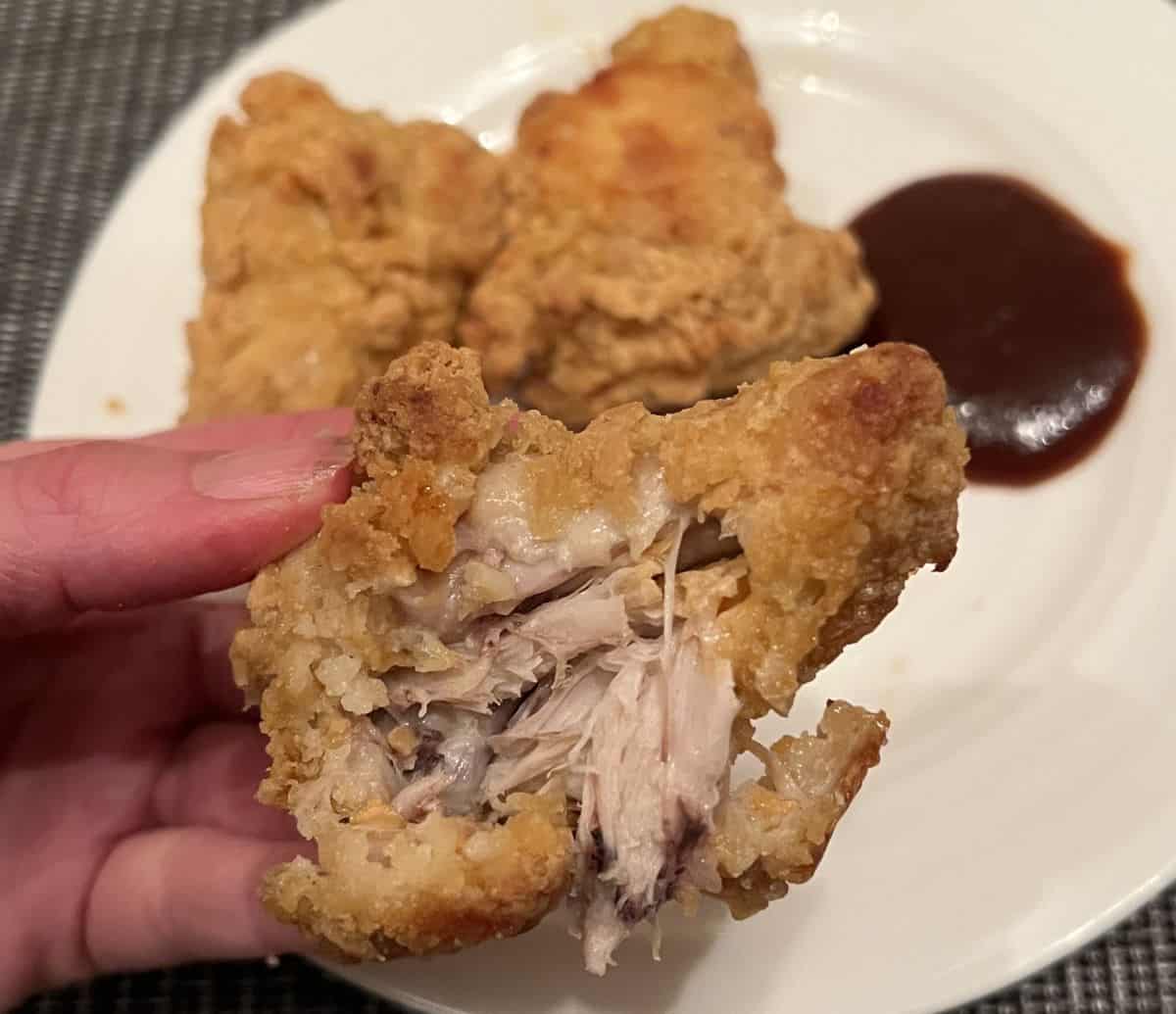 Image of a hand holding a chicken wing with a few bites taken out so you can see the center.