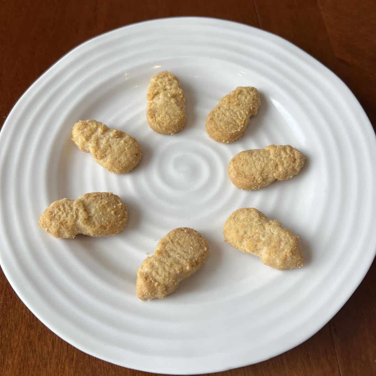 Image of seven pineapple shaped cookies served on a white plate.