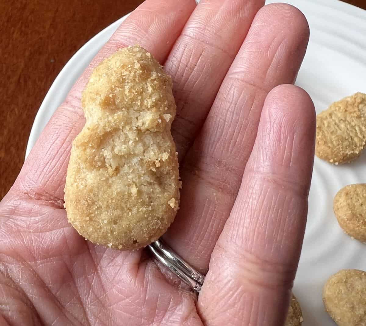 Closeup image of a hand holding one pineapple cookie. 