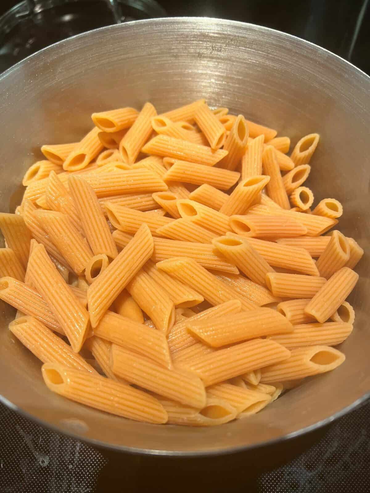 Image of a pot of cooked pasta penne sitting on a stovetop.