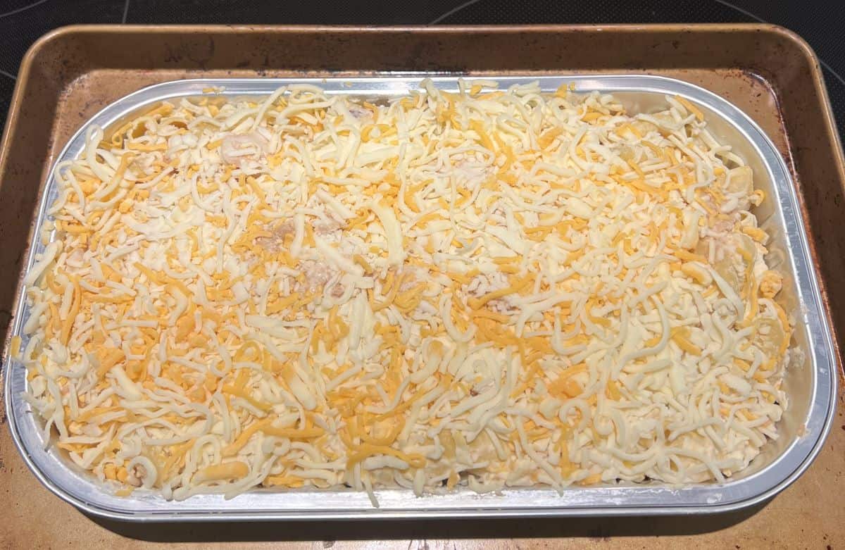 Image of the chicken and bacon mac and cheese tray sitting on a cookie tray with the lid off prior to going in the oven.