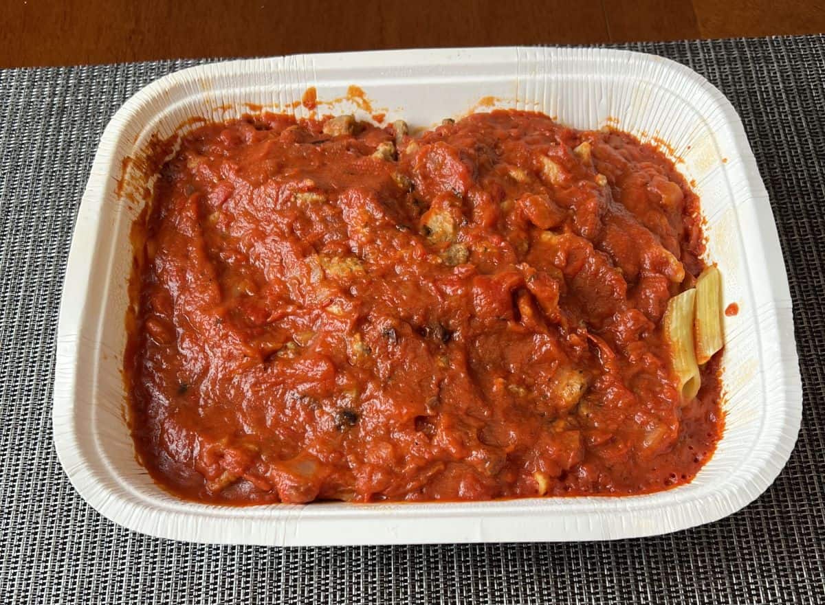 Image of a tray of penne with red tomato sauce on top. 