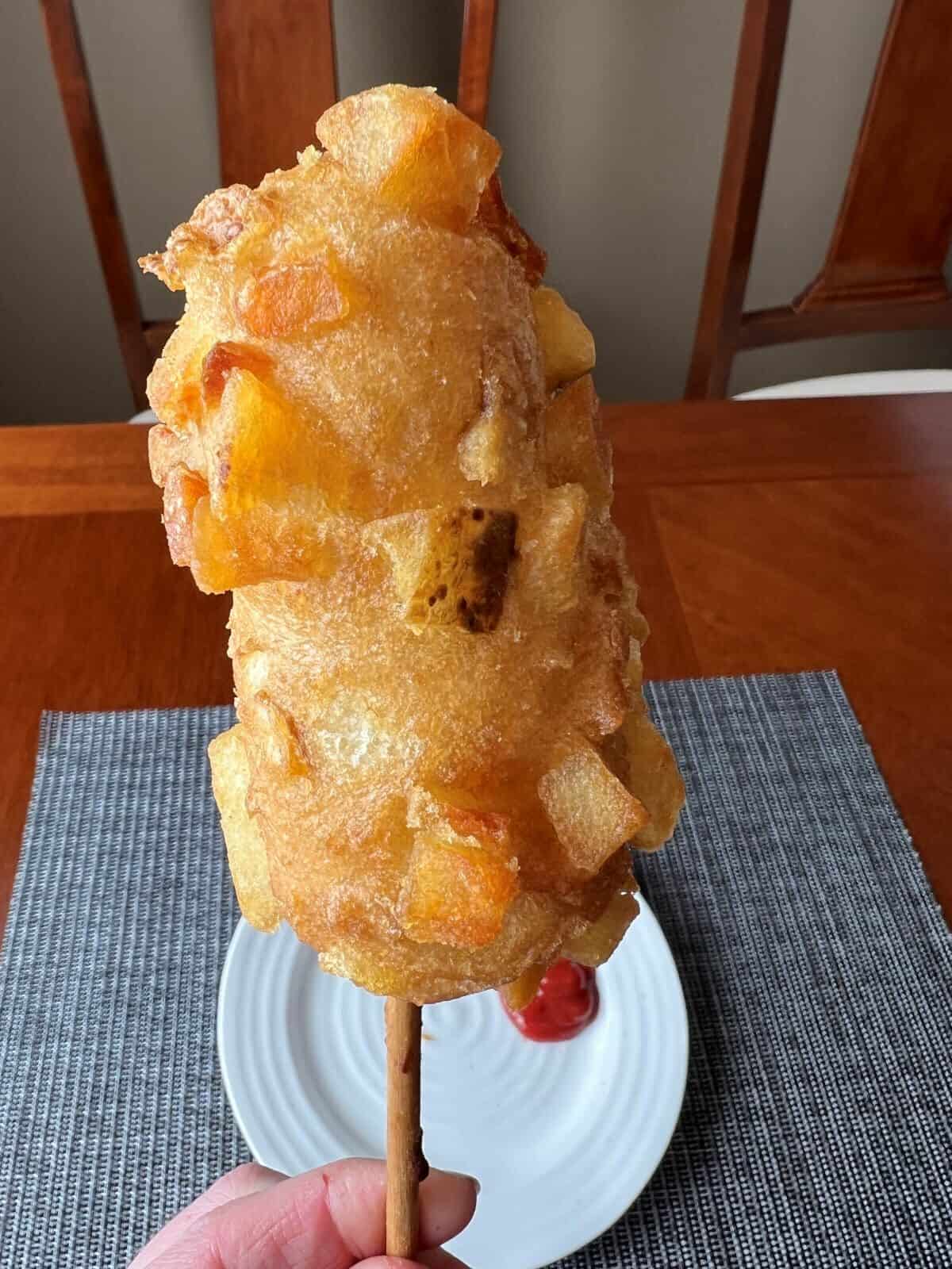 Closeup image of a crispy potato corn dog that's been heated.