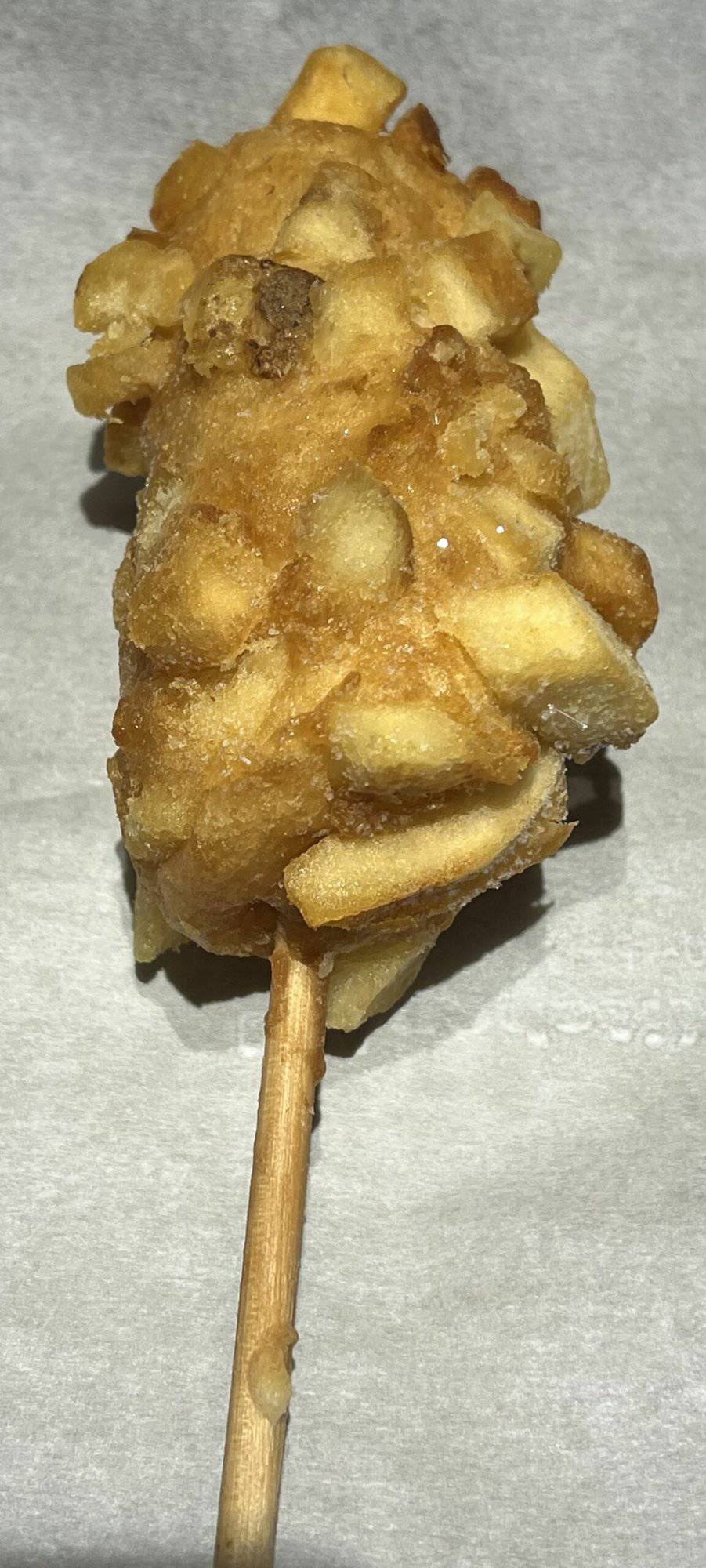 Image of a frozen potato corn dog on a parchment lined baking sheet prior to being baked.