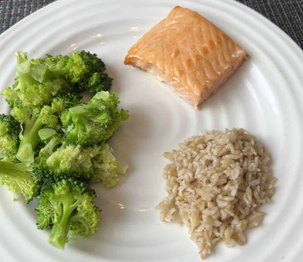 Image of a piece of salmon served beside a side of broccoli and a bed of rice.