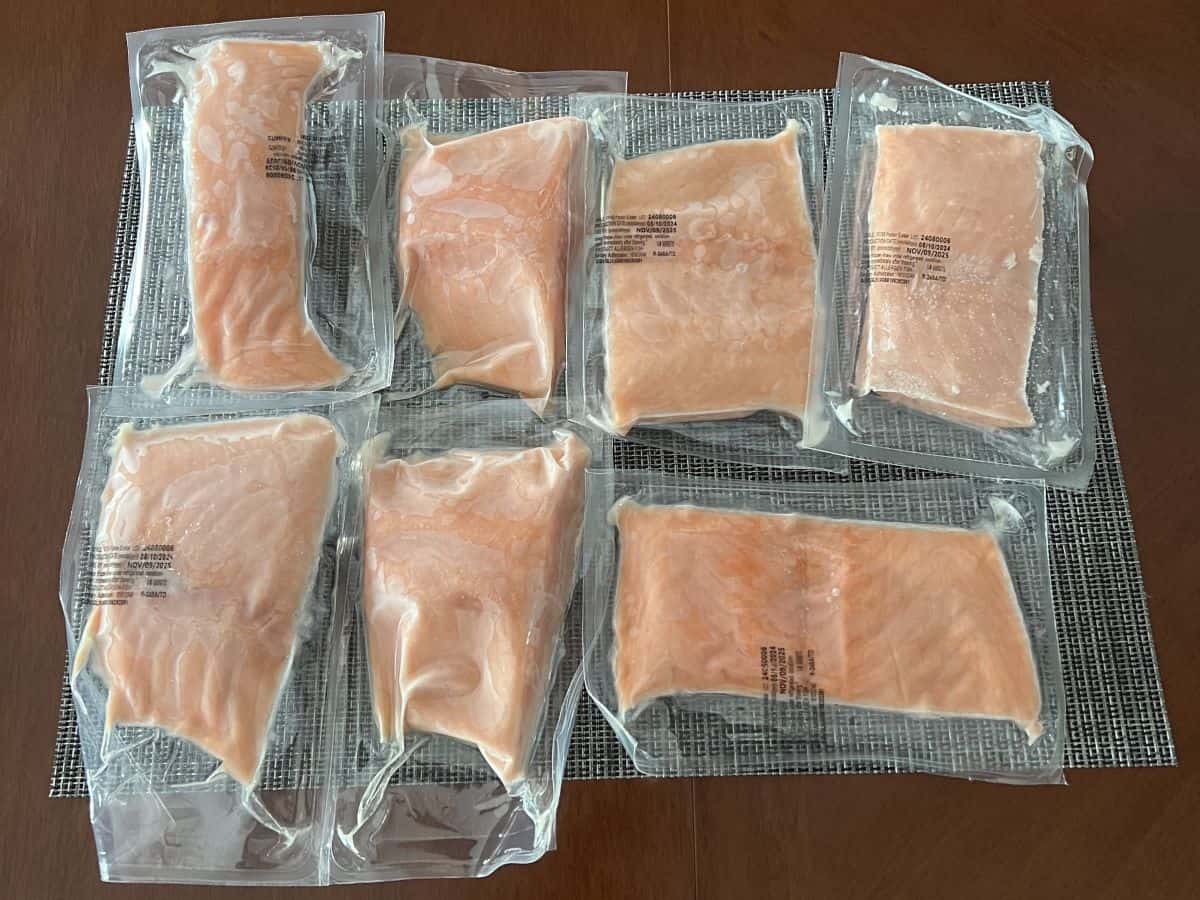 Image of seven vacuum sealed portions of frozen salmon sitting on a table.