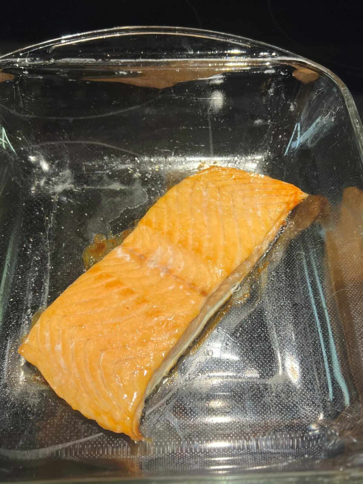 Closeup image of a cooked piece of salmon in a baking dish.