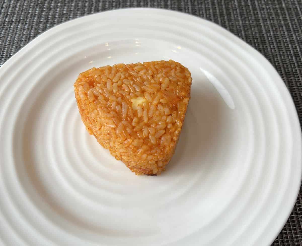 Top down image of one cooked rice ball served on a white plate.