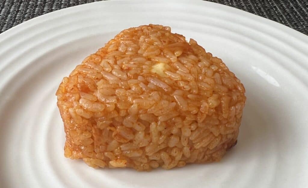 Closeup image of one rice ball cooked and served on a white plate.