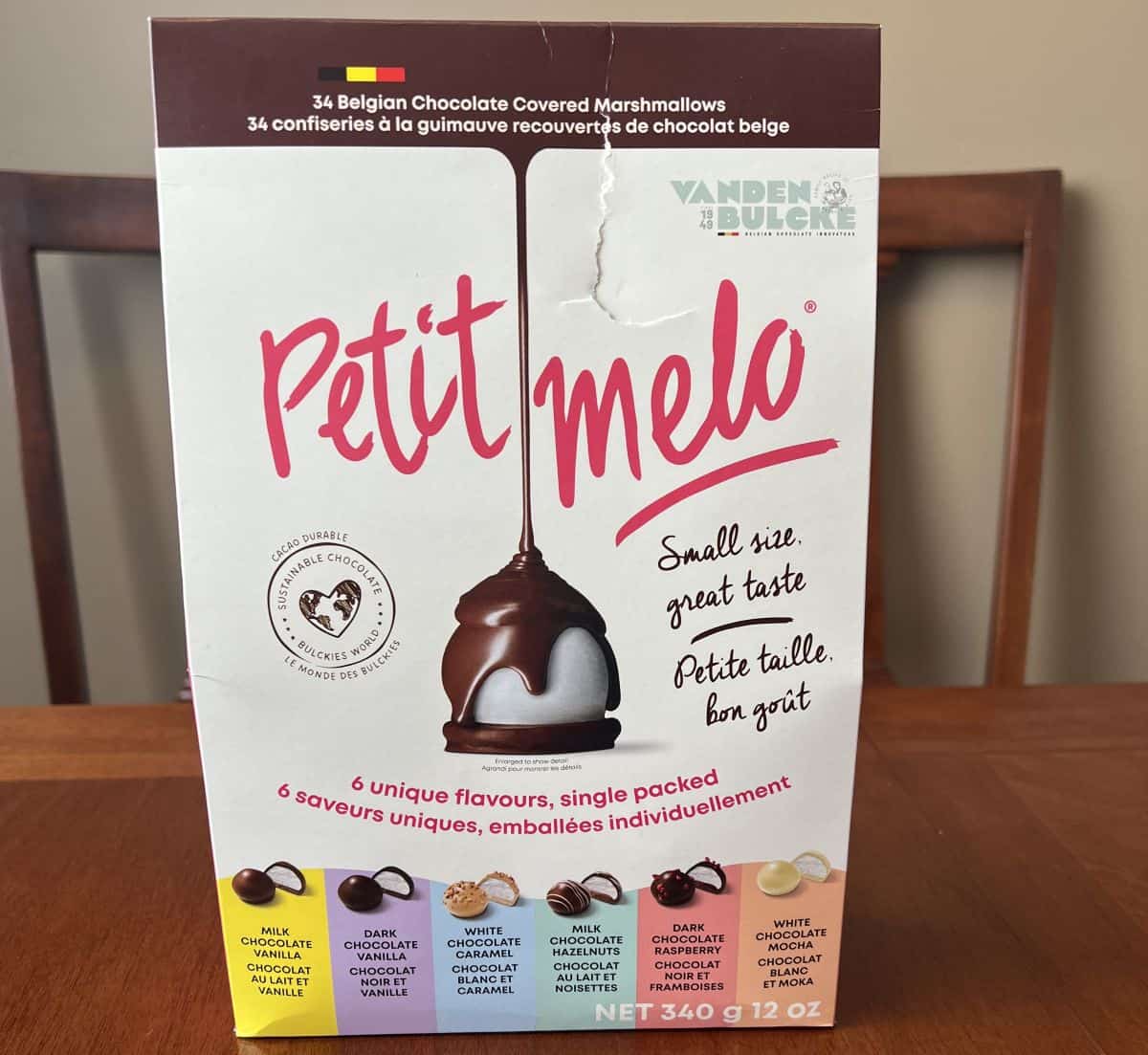 Image of the box of Petit Melo Chocolate Covered Marshmallows sitting on a table unopened.