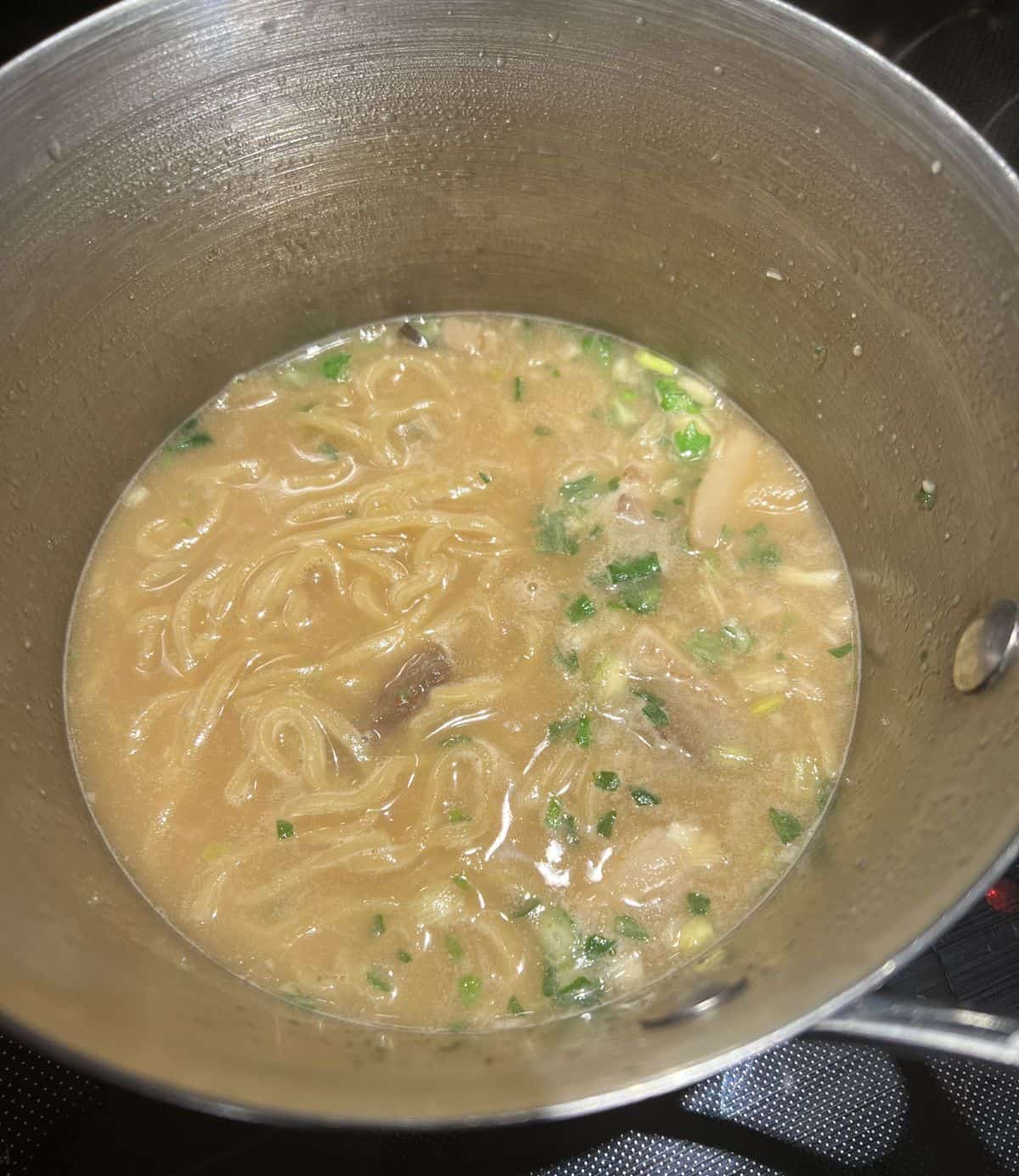 Image of a pot of ramen being cooked on a stove.