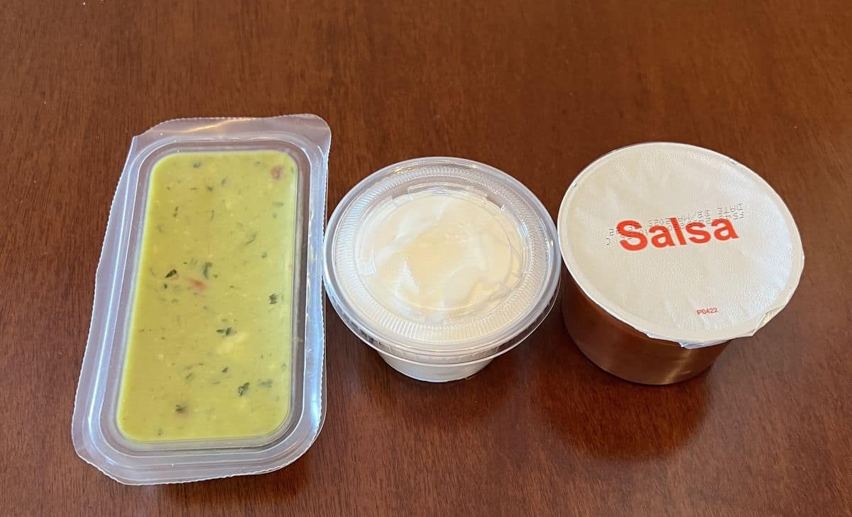 Image of sealed containers of guacamole, sour cream and salsa that come with the quesadillas.