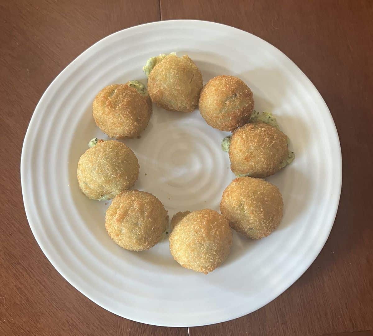 Image of the spinach & artichoke bites baked and served on a white plate.