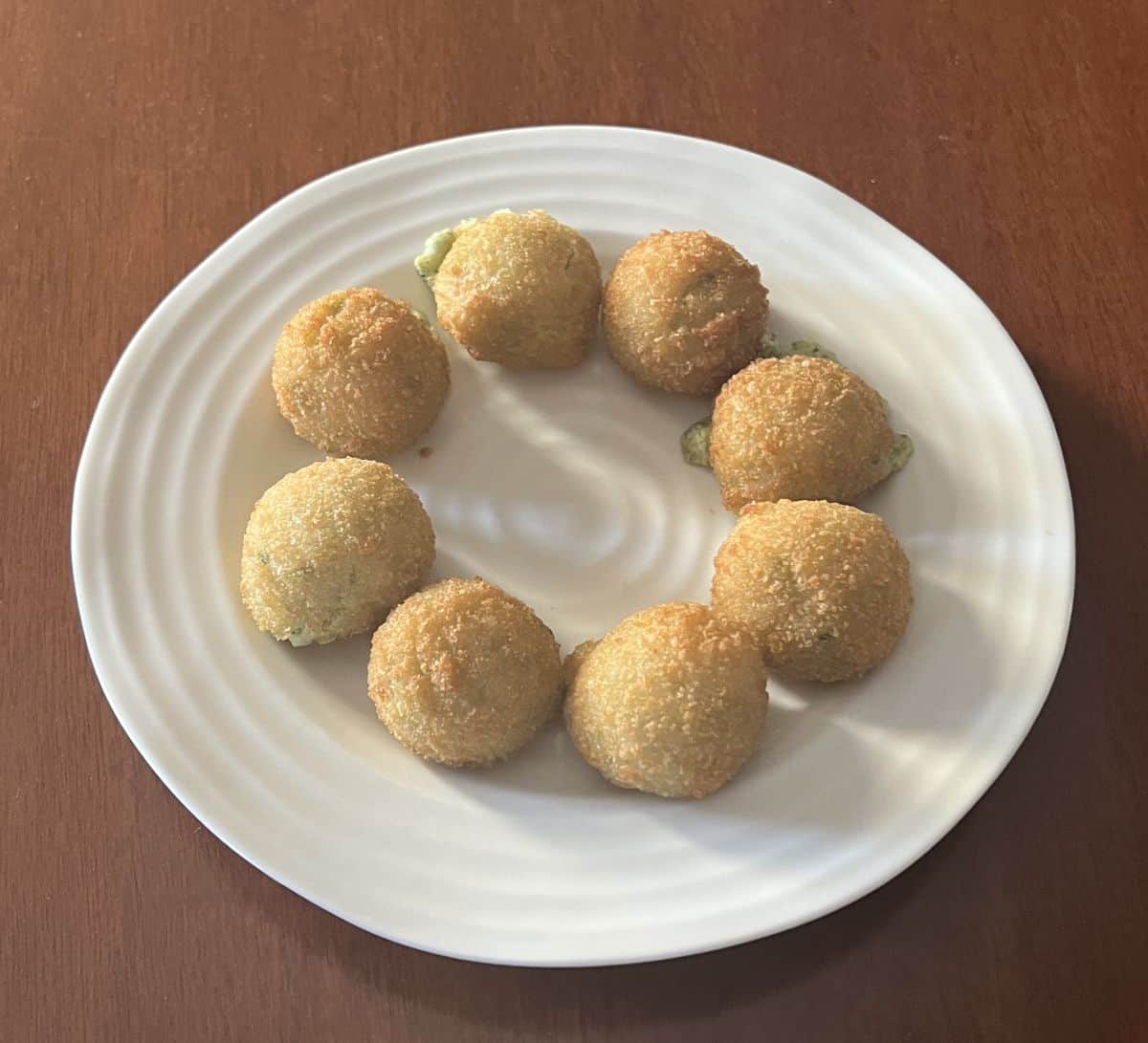 Image of the spinach & artichoke bites baked and served on a white plate.